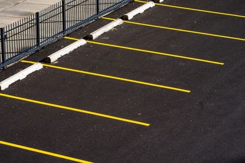 Top view of an empty parking lot with yellow lines and a metal fence, perfect for urban scenes.